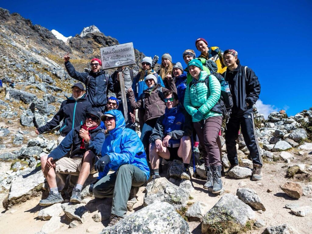 Caminantes en el paso de montaña del Salkantay con el nevado al fondo